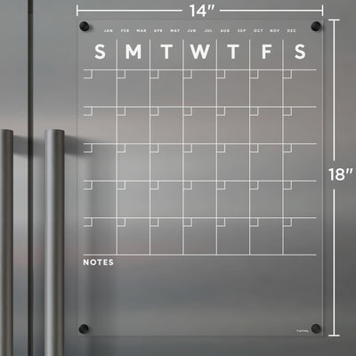 The Girl Friday Shops Clear Acrylic Monthly Fridge Calendar features a grid layout, spans Sunday to Saturday, measures 14x18 inches, and adheres magnetically. It includes a bottom Notes section ideal for jotting with wet-erase markers in white text.