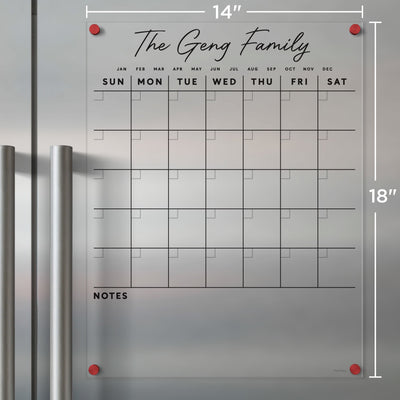 Girl Fridays Clear Acrylic Monthly Calendar for fridge, customized with The Geng Family, displays a monthly grid with daily labeled rows. It includes a NOTES section for wet-erase markers, measures 14x18, and features stylish red corner mounts.