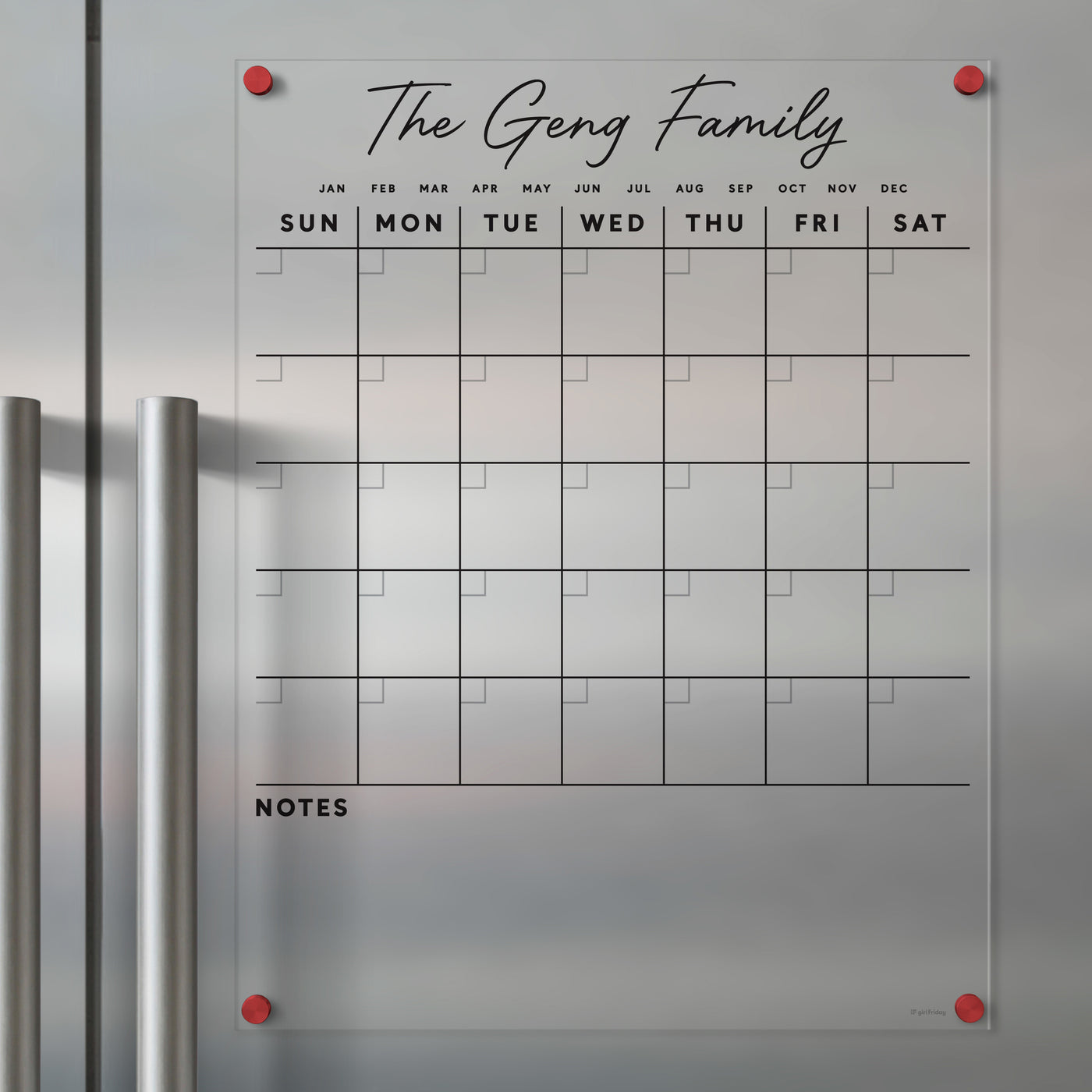 The Clear Acrylic Monthly Magnetic Fridge Calendar by Girl Friday clings to metal surfaces with red magnets. It has columns for each day, Sunday to Saturday, and a notes section. Titled with The Geng Family in script font, it allows easy updates using wet-erase markers.