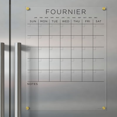 The Girl Friday Clear Acrylic Monthly Magnetic Fridge Calendar features FOURNIER at the top, labeled days of the week, spaces for each month, and a NOTES section. Perfect for wet-erase markers, it mounts easily on any metal surface with visible handles.