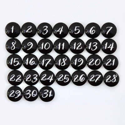 CalendarGirlCompanys #920 product features 31 black circular magnets resembling a chalkboard menu, each with white handwritten numbers from 1 to 31, arranged in rows on a clean white surface.