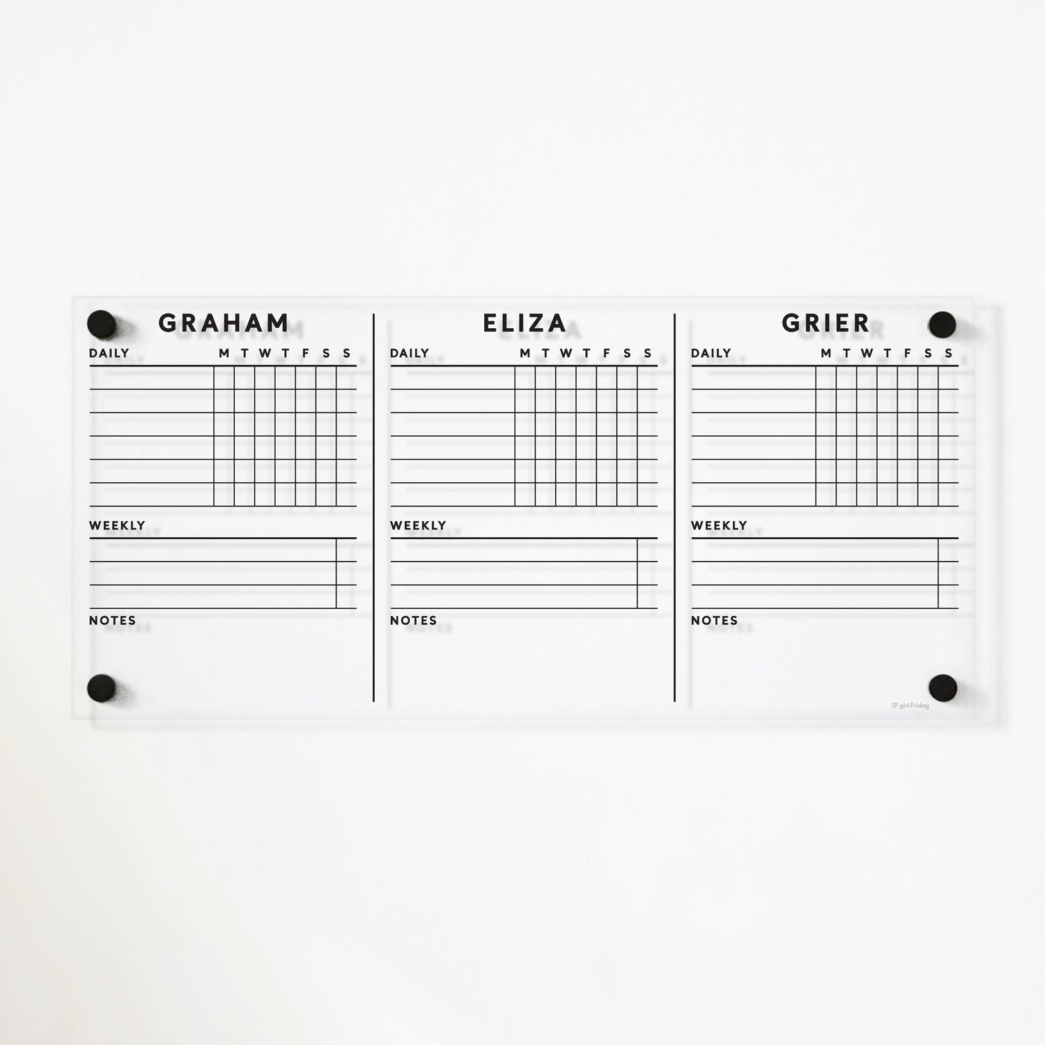 The Girl Friday Acrylic Chore Chart for wall is a personalized board with sections labeled Graham, Eliza, and Grier. It organizes daily and weekly tasks with notes Monday to Sunday. Wet-erase markers are used on its sleek surface, mounted efficiently using round black pins.