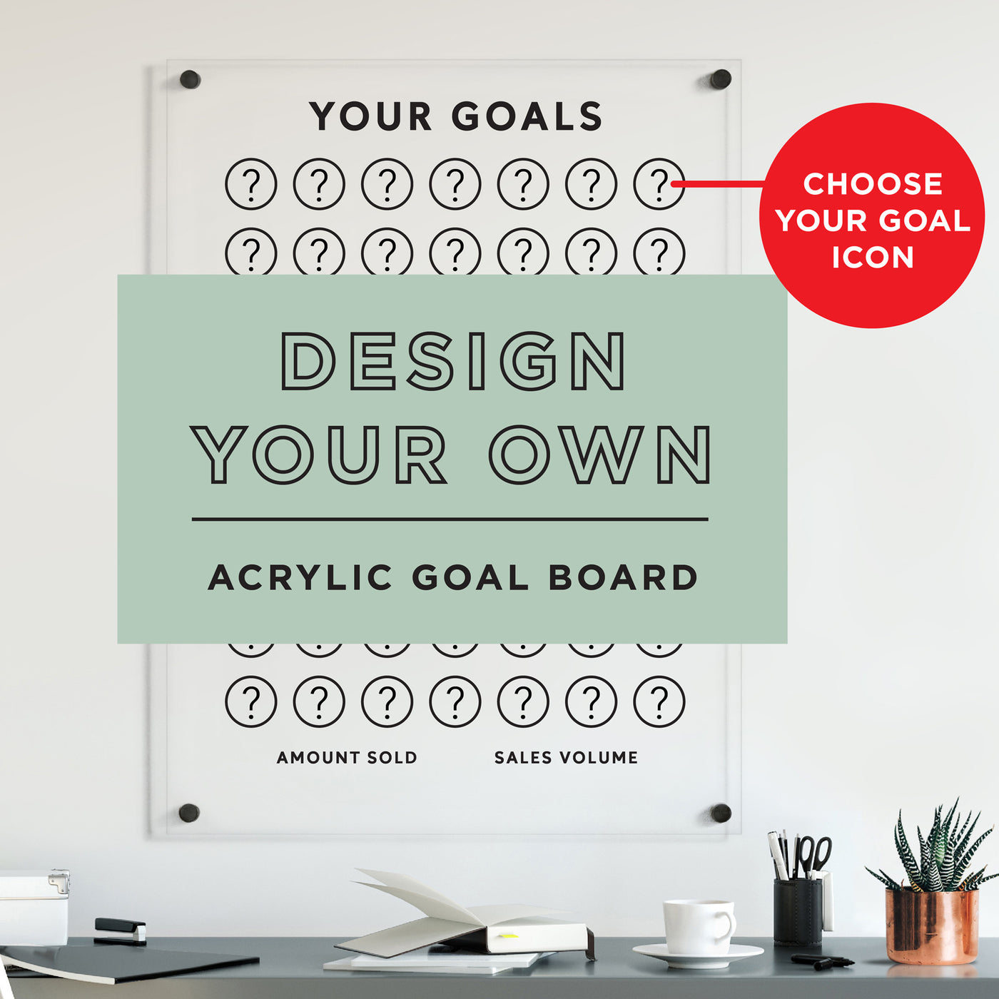 A minimalist workspace showcases an acrylic Goal Chart by Girl Friday, labeled Design Your Own Icon, with a grid of question marks and a highlighted red circle for choosing your custom icon. Desk items include a notebook and pens.