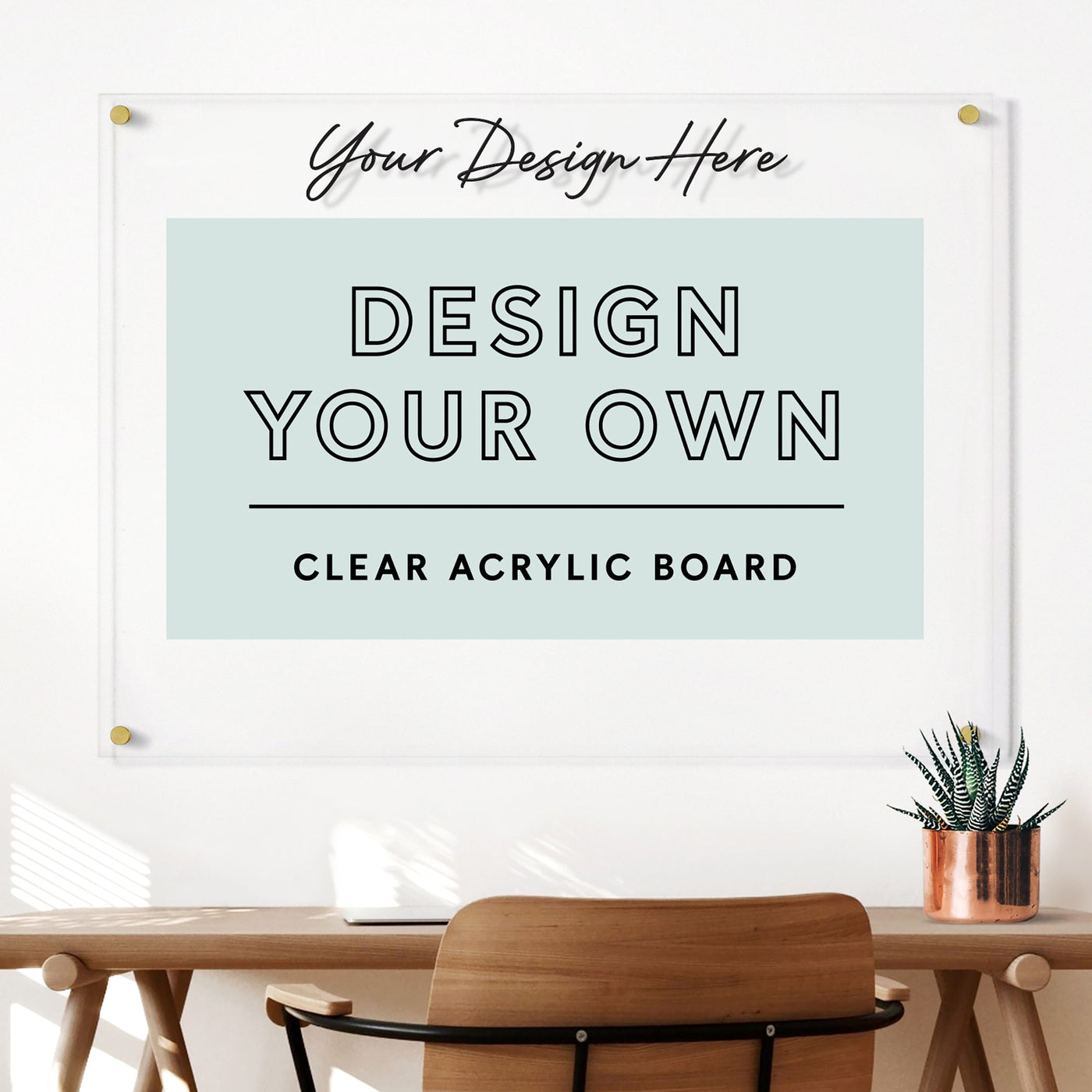 A contemporary workspace includes a wooden chair, desk with a plant, and the Girl Friday Shops Clear Acrylic Design Your Own Board in horizontal format above. Customize your board with wet-erase markers and add personal flair to your space.