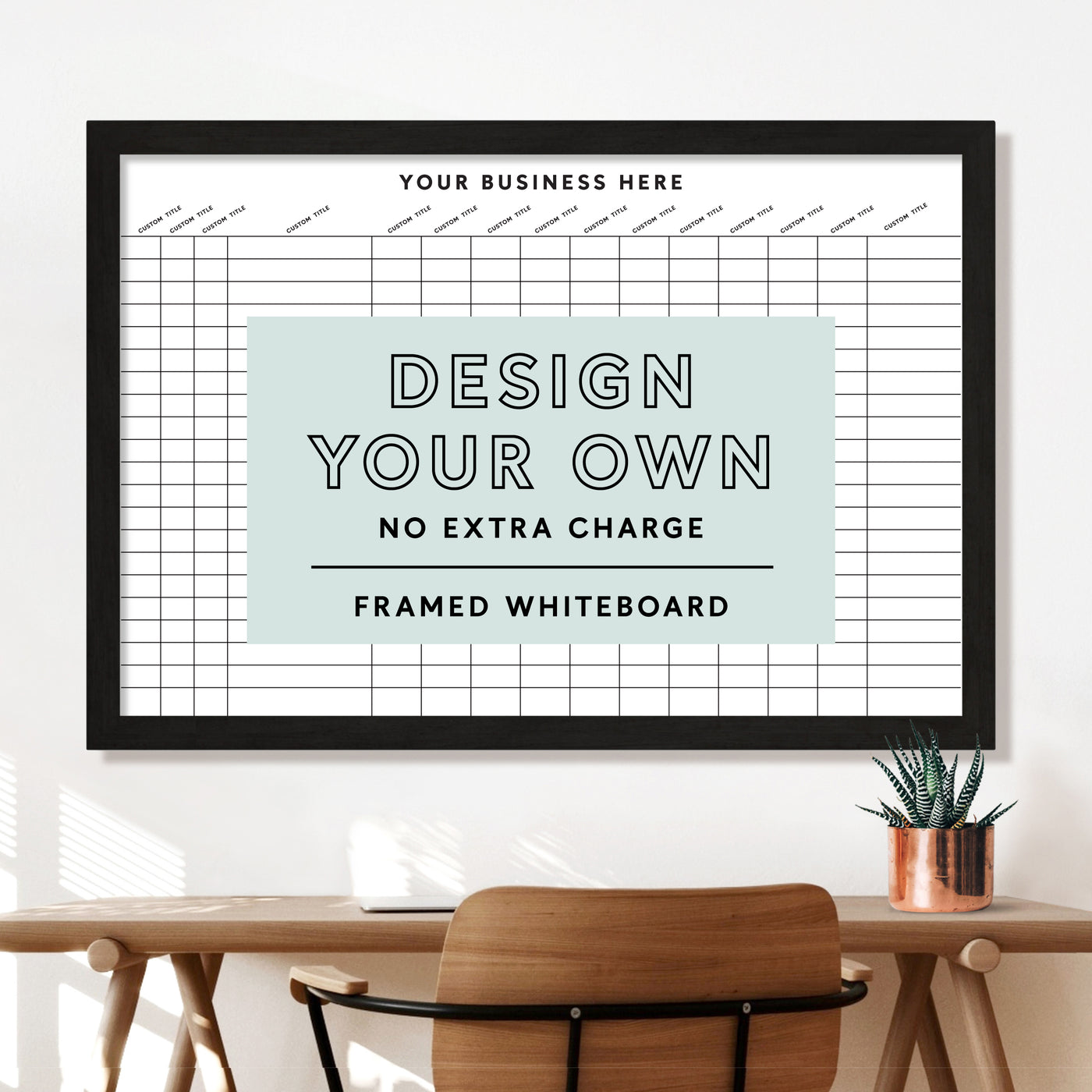 A Design Your Own Framed Tracking Whiteboard | Horizontal by Girl Friday Shop hangs above a wooden table with a chair. A potted plant sits on the table. The board has rows and columns for planning, inviting you to customize its frame and create your unique design.