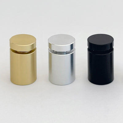 Three cylindrical acrylic signs with flat tops sit in a row on a plain background. From left to right, they are gold, silver, and black. Each sign boasts a sleek finish akin to a custom design masterpiece by Girl Friday Shop.