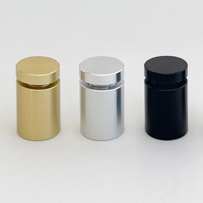 Three elegant cylindrical bottles with rounded caps, colored gold, silver, and black, stand against a plain backdrop reminiscent of Girl Friday Shops Please Do Not Ring Door Bell acrylic sign.