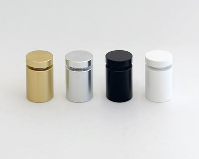 Four cylindrical bottles with caps, left to right in gold, silver, black, and white, gleam on a plain light gray surface. This arrangement mirrors the refined elegance typical of an Acrylic Art print designed by a talented Ukrainian artist from Girl Friday.