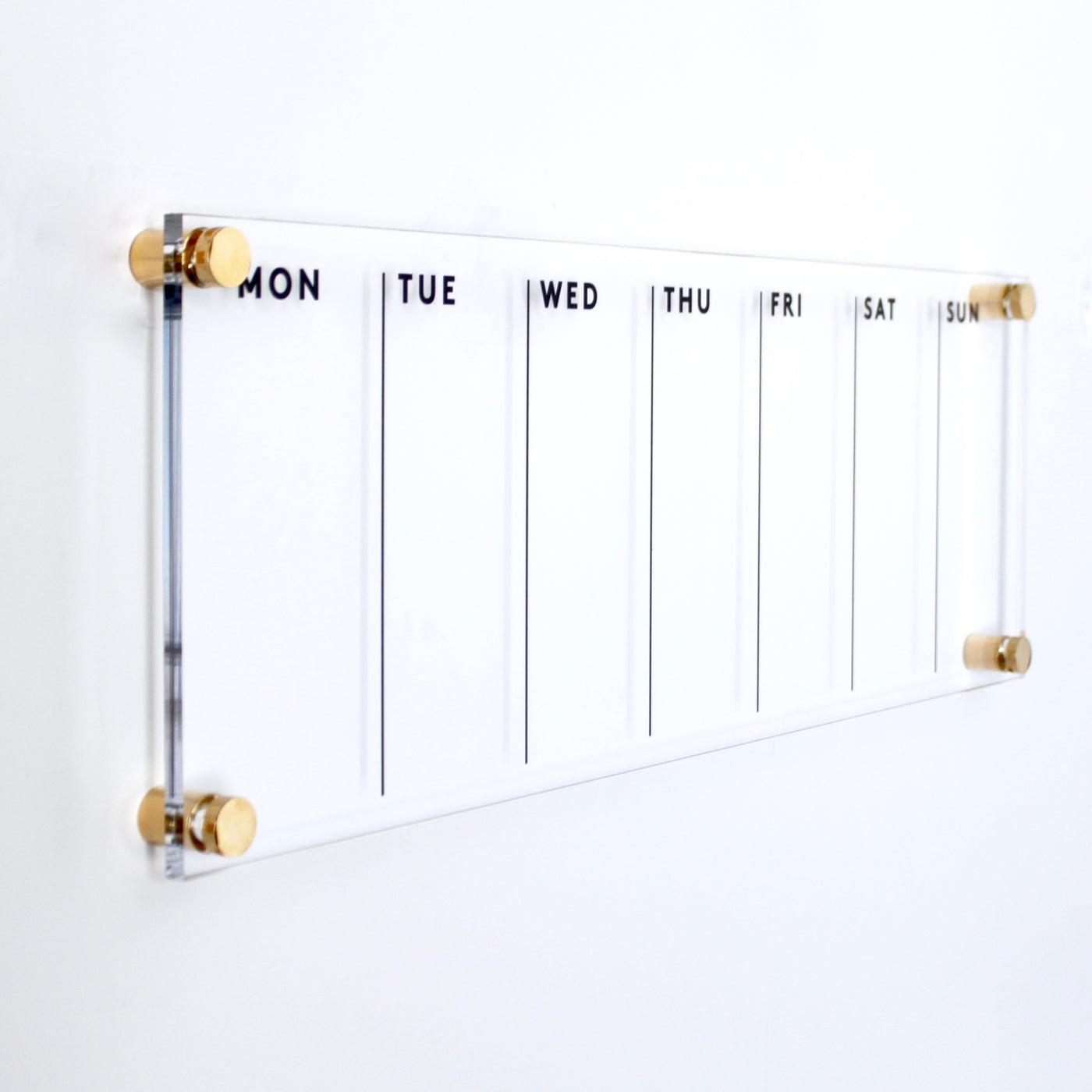 The Girl Friday Shops Acrylic Calendar - Weekly is a high-quality wall planner with sections from MON to SUN in sleek black text. It mounts with gold standoffs on a white background and pairs perfectly with a wet-erase marker for easy updates.