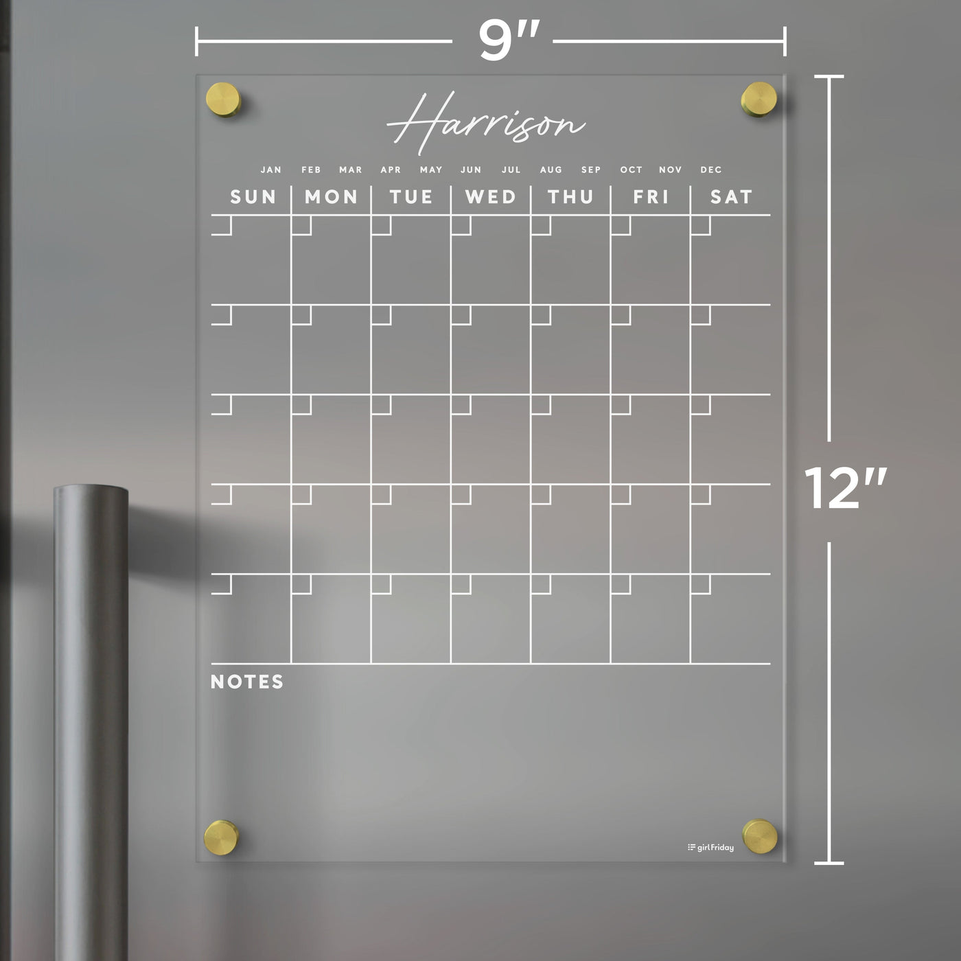 The Harrison by Girl Friday is a 9x12-inch clear acrylic wall calendar with a Sunday-start grid layout, note space at the bottom, and gold corner mounts. Its compatible with dry-erase markers and perfect for home office or fridge use.