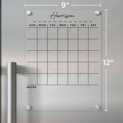 A stylish 9x12-inch Girl Friday Clear Acrylic Monthly Calendar for your fridge, customizable with Harrison. It includes labeled days, empty squares, and a notes section. Ideal for flexible planning with wet-erase markers.