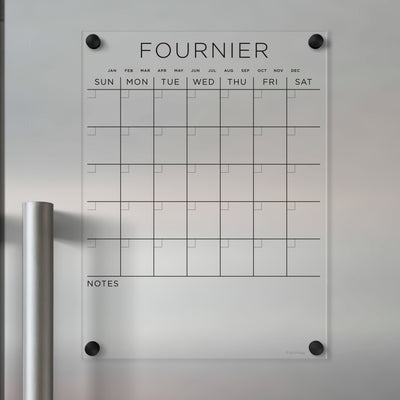 The Clear Acrylic Monthly Magnetic Fridge Calendar | Custom Family Name by Girl Friday is a transparent, customizable calendar with labeled months and days. It has sections for daily plans, a Notes area, and mounts to metallic surfaces, ideal for wet-erase markers.