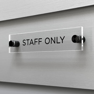 A custom-designed Girl Friday Shop Staff Only Acrylic Sign with bold black text is mounted on a sleek gray wall.