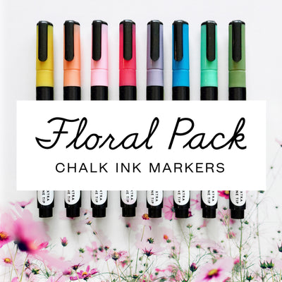 Nine vibrant markers from yellow to green, set against light pink flowers, form the Girl Friday Shops Floral Chalk Ink Marker Set. The set features an extra fine tip for precision on acrylic boards.