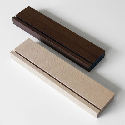 The Girl Friday Weekly Black Acrylic Calendar with Wood Stand features two rectangular wooden blocks in dark brown and light beige, each with a narrow groove. Theyre perfect for organizing your desk or calendar notes with style on a white surface.