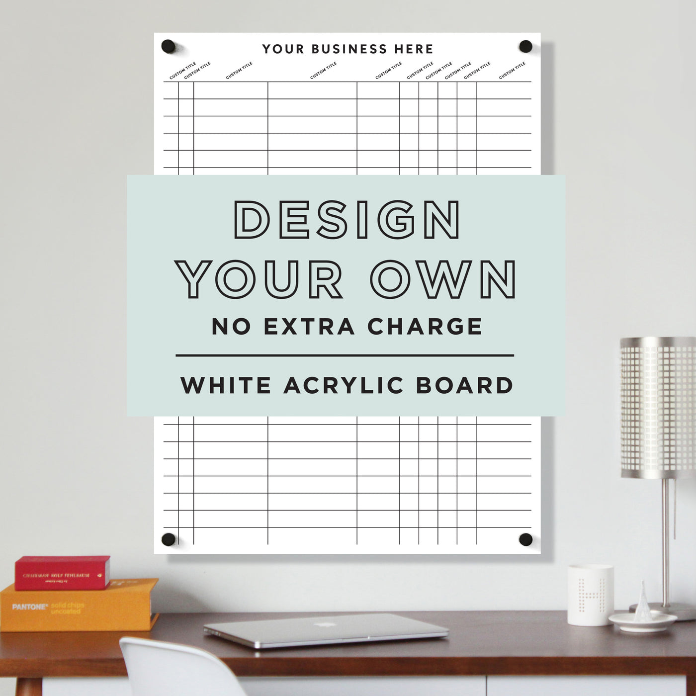 A Girl Friday vertical wall-mounted white acrylic board with a customizable design option is displayed, showcasing its dry-erase surface. A text overlay reads: Design Your Own, with no extra charge. Nearby, a lamp adorns the desk.