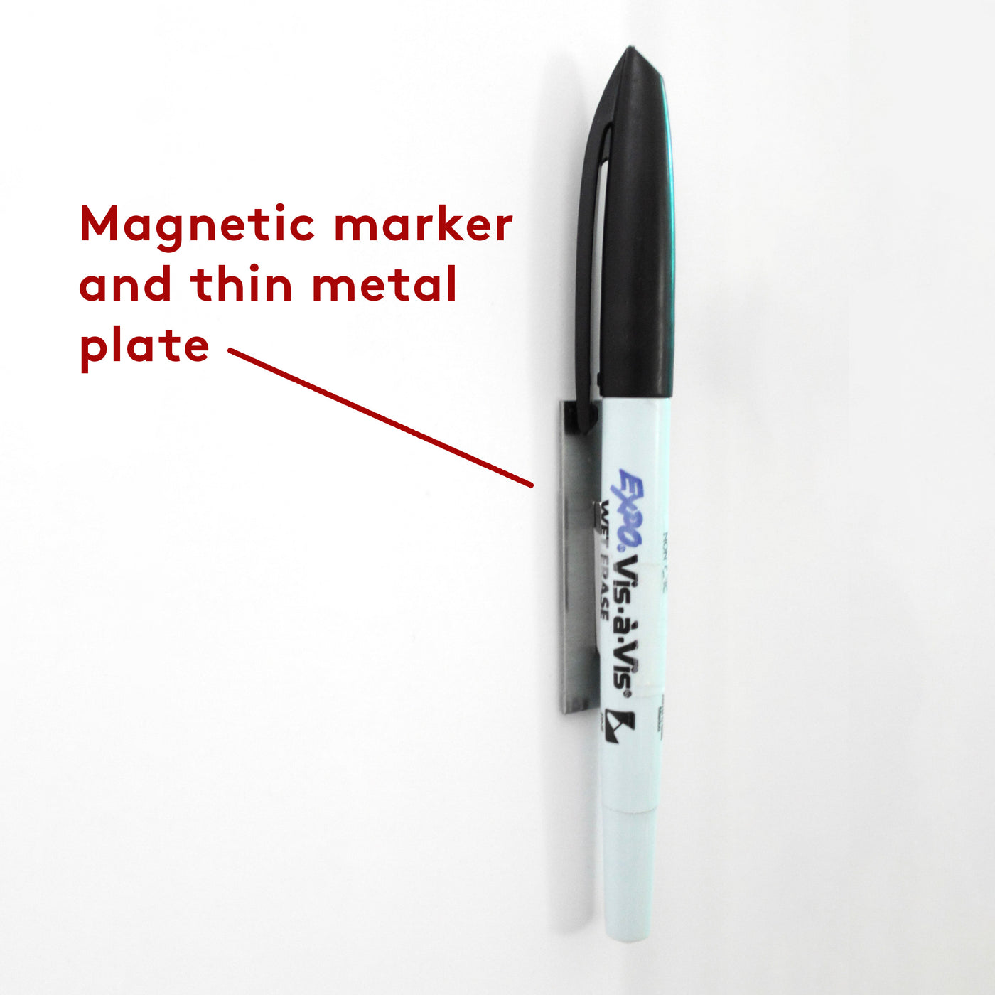 A white and black Expo Vis-a-Vis marker is attached to the surface of a Girl Friday Shop White Acrylic Chore Chart, using a thin metal plate with a red arrow pointing to it, labeled Magnetic marker and thin metal plate.