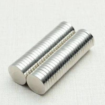 Two stacks of Girl Friday Shops strong neodymium disk magnets, each small and round with a shiny metallic finish and N35 strength, are arranged side by side on a light surface. Their cylindrical shape is clearly visible.