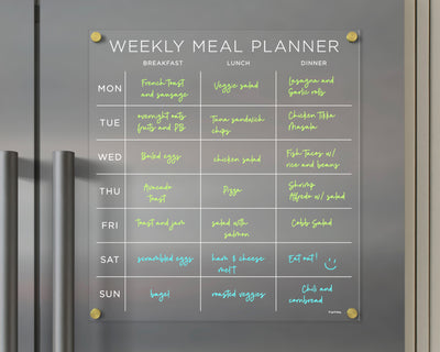 The Girl Friday Shops Clear Acrylic Fridge Meal Planner is a magnetic tool for weekly meal organization. With neon text on a grey background, it includes options like bagels and salads. Update plans daily with wet-erase markers for breakfast, lunch, and dinner.