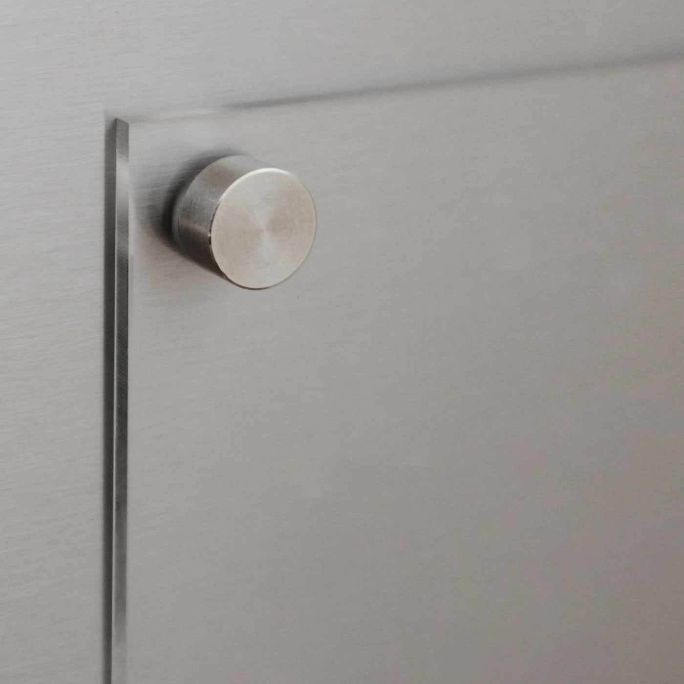 A close-up of a brushed metal surface with a metallic knob, its sleek reflective finish is reminiscent of the modern design seen in Girl Friday Shops Clear Acrylic Fridge Meal Planner.