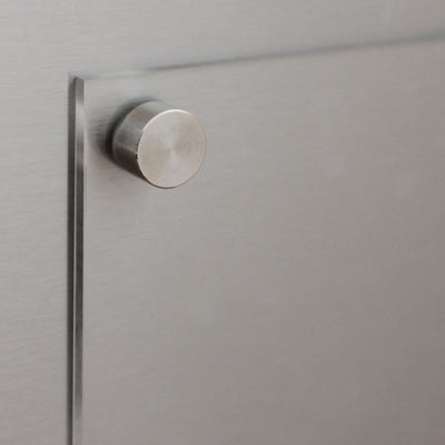 A close-up of a brushed metal surface with a metallic knob, its sleek reflective finish is reminiscent of the modern design seen in Girl Friday Shops Clear Acrylic Fridge Meal Planner.