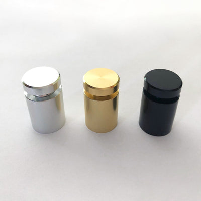 Three metallic cylindrical standoffs in silver, gold, and black support the Large Acrylic Calendar with Bottom Notes from Girl Friday Shop on a white surface. Each has a screw top and smooth finish, ideal for wet-erase markers.