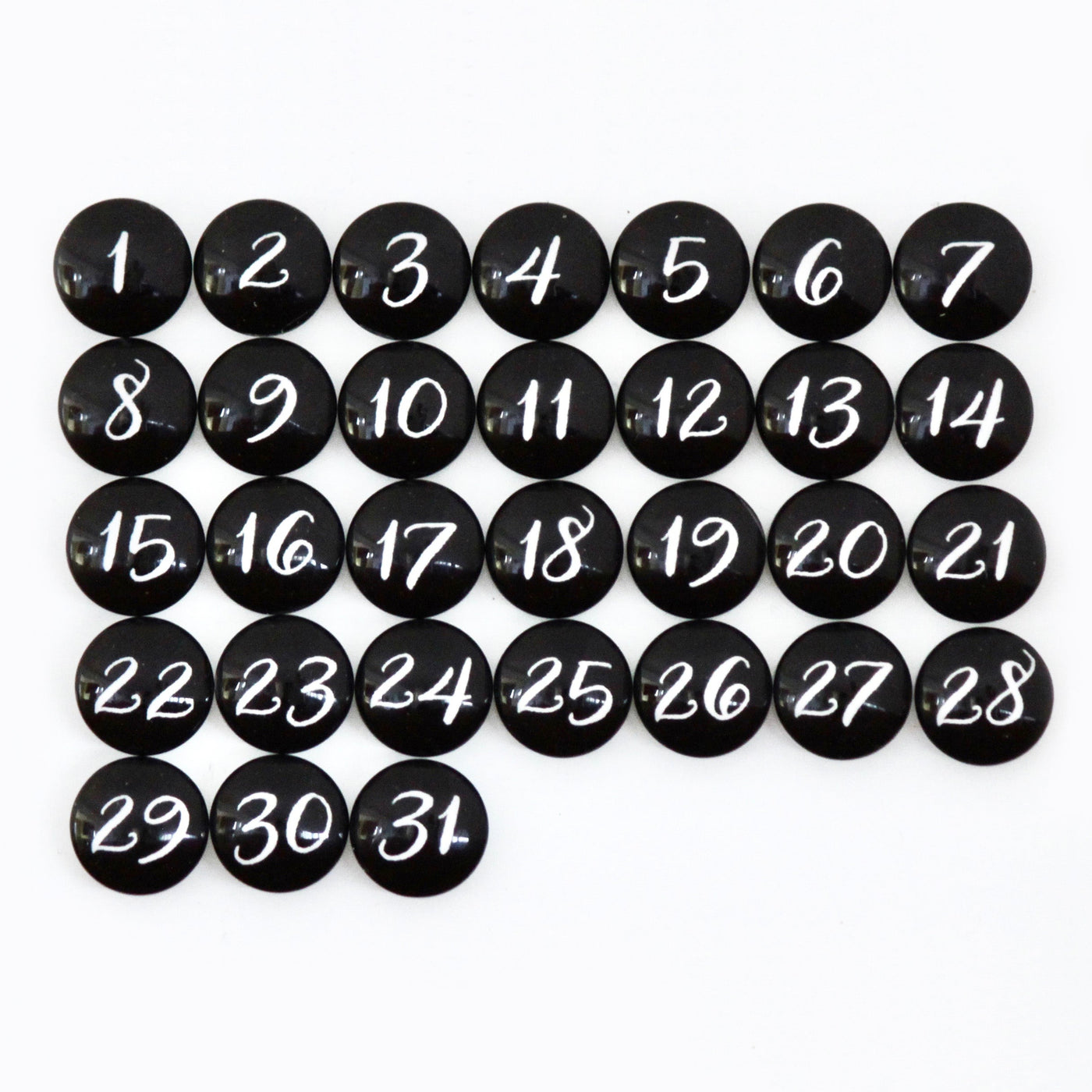 Black circular magnets numbered 1-31 in white script are arranged on a grid pattern against the premium CalendarGirlCompanys 24 x 18 Framed Whiteboard Calendar.