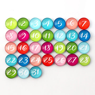 Colorful round magnets numbered 1-31 adorn a white surface in five rows with vibrant hues like green, blue, pink, red, and purple. These playful magnets evoke chalk ink markers and are perfect for customizing your CalendarGirlCompany 36 x 24 Framed Chalkboard Calendar (#24126).
