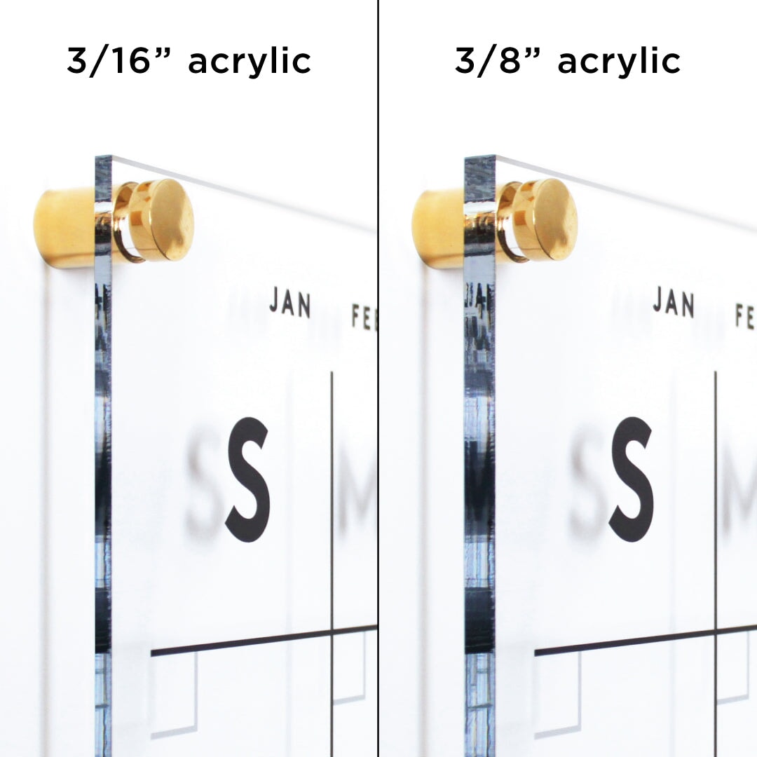 Two acrylic panels with gold standoffs showcase the Girl Friday Shops Clear Acrylic Monthly Wall Calendar with Notes | Horizontal. Labeled 3/16” acrylic (left) and 3/8” acrylic (right), both panels have a visible calendar section for planning using wet-erase markers.