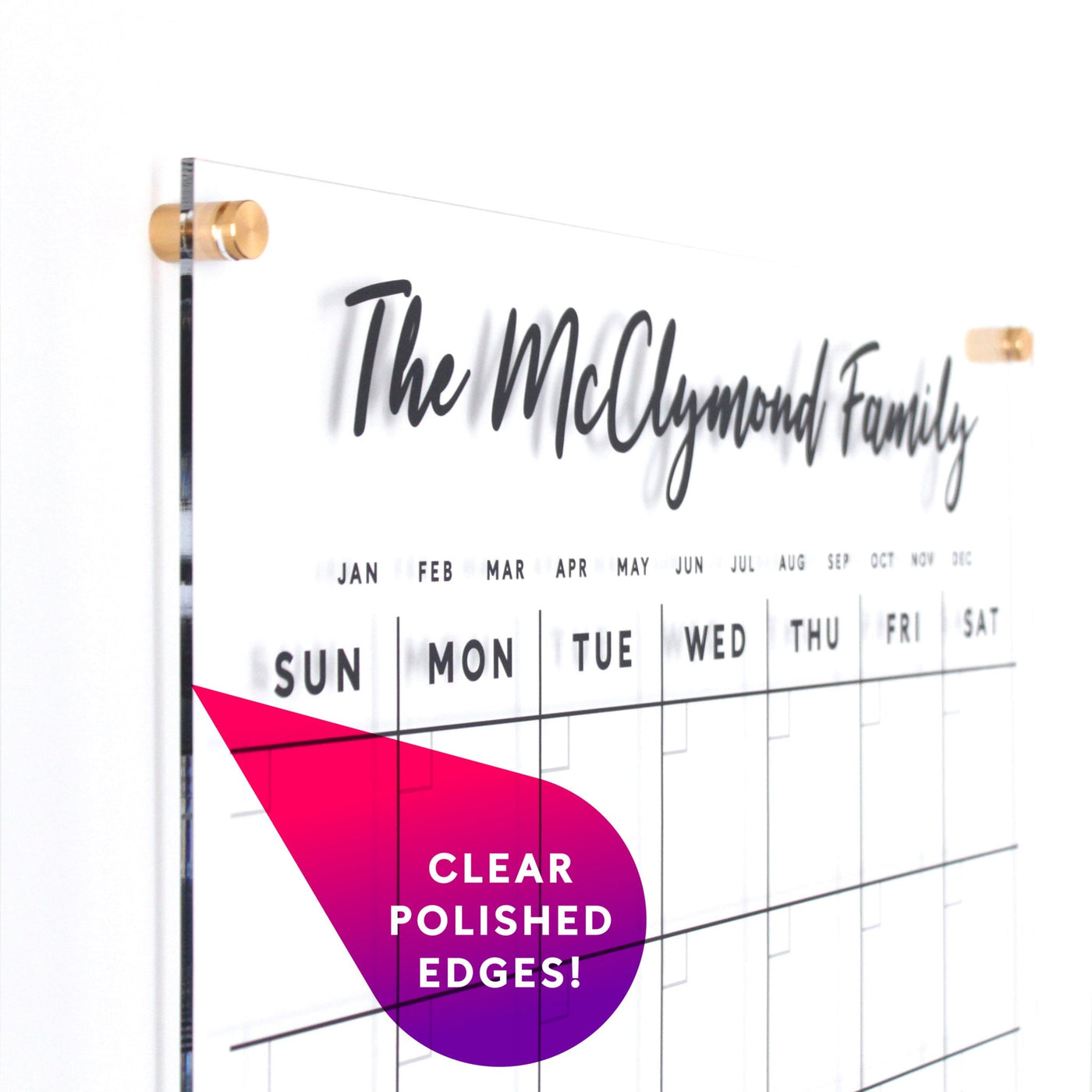 The Clear Acrylic Customizable Monthly Wall Calendar by Girl Friday Shop highlights The McClymond Family in script font at the top. It includes day columns and labeled months. Stylish pink shapes showcase Clear Polished Edges! Its elegantly mounted with gold standoffs for a refined appearance.
