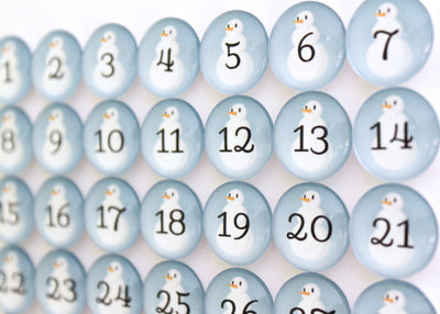 Close-up of Girl Fridays Number Magnets - Snowmen set showing a winter calendar grid of round, light blue magnets with snowmen and black numbers 1 to 42; each Frosty has a tiny orange nose.
