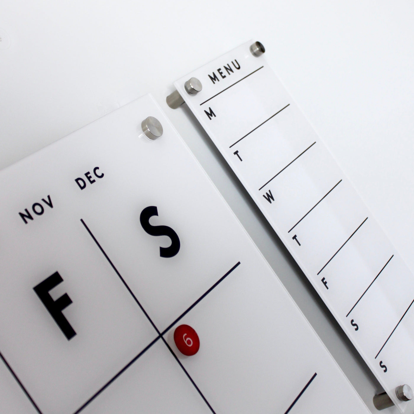 A calendar shows late November and early December, marked on the 6th. Beside it is Girl Friday Shops sleek Magnetic Acrylic Menu Board, featuring abbreviated weekdays for weekly planning. Both items are white with black text.