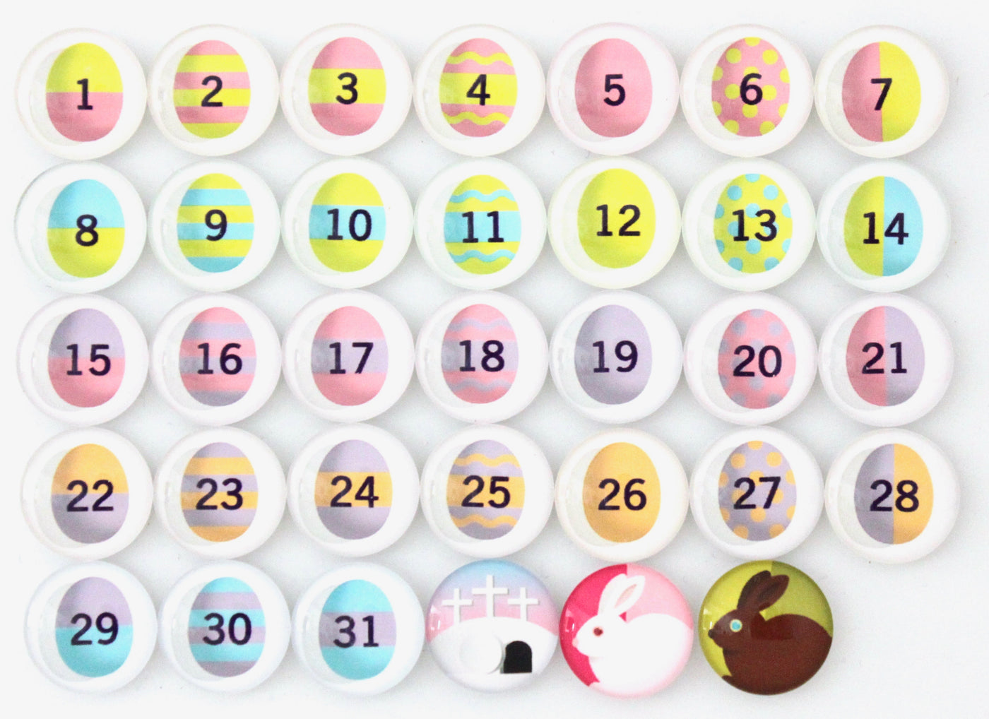 The Girl Friday Number Magnets for April! Easter Bunny | Easter Eggs set features 31 numbered circles with unique Easter egg designs, and two glass magnets at the bottom right displaying white and brown bunnies, ideal for celebrating Aprils festive spirit.