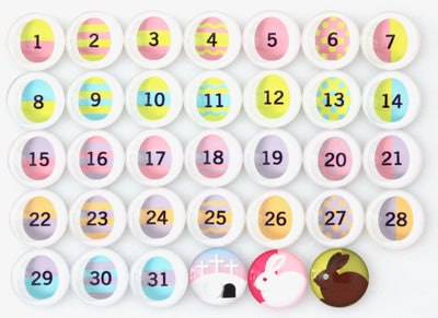 The Girl Friday Number Magnets for April! Easter Bunny | Easter Eggs set features 31 numbered circles with unique Easter egg designs, and two glass magnets at the bottom right displaying white and brown bunnies, ideal for celebrating Aprils festive spirit.