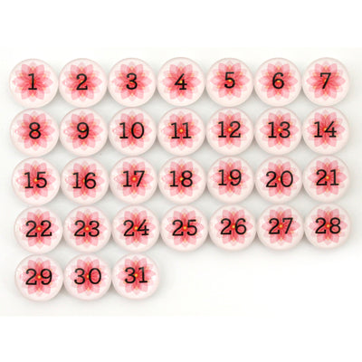Girl Fridays Number Magnets for May showcase a 5x7 grid of white circles with bold black numbers (1-31) and a red floral pattern, resembling a Spring flowers calendar. These charming magnets add seasonal flair and decorative beauty to any space.