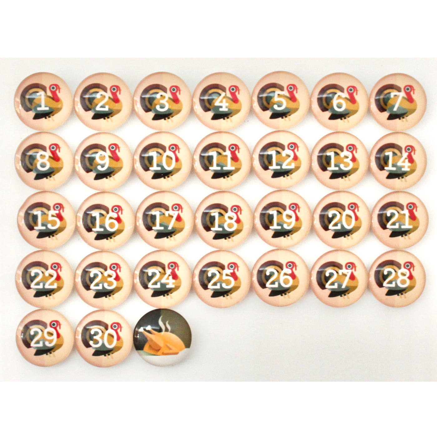 The Girl Friday Number Magnets - Thanksgiving! Turkey Day set features circular magnets numbered 1-30, each with a turkey design. Ideal for kids, it includes a special glass magnet at the bottom displaying a cornucopia image instead of a number.