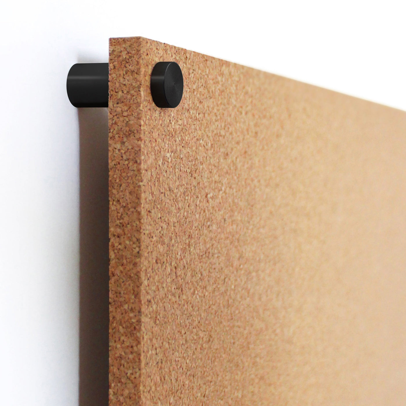 A close-up of the Modern Cork Board with dots by Girl Friday Shop shows its textured cork corner mounted on a wall. A black circular bracket holds it in place, allowing for personalization with push pins, against a backdrop where the wall subtly peeks through.