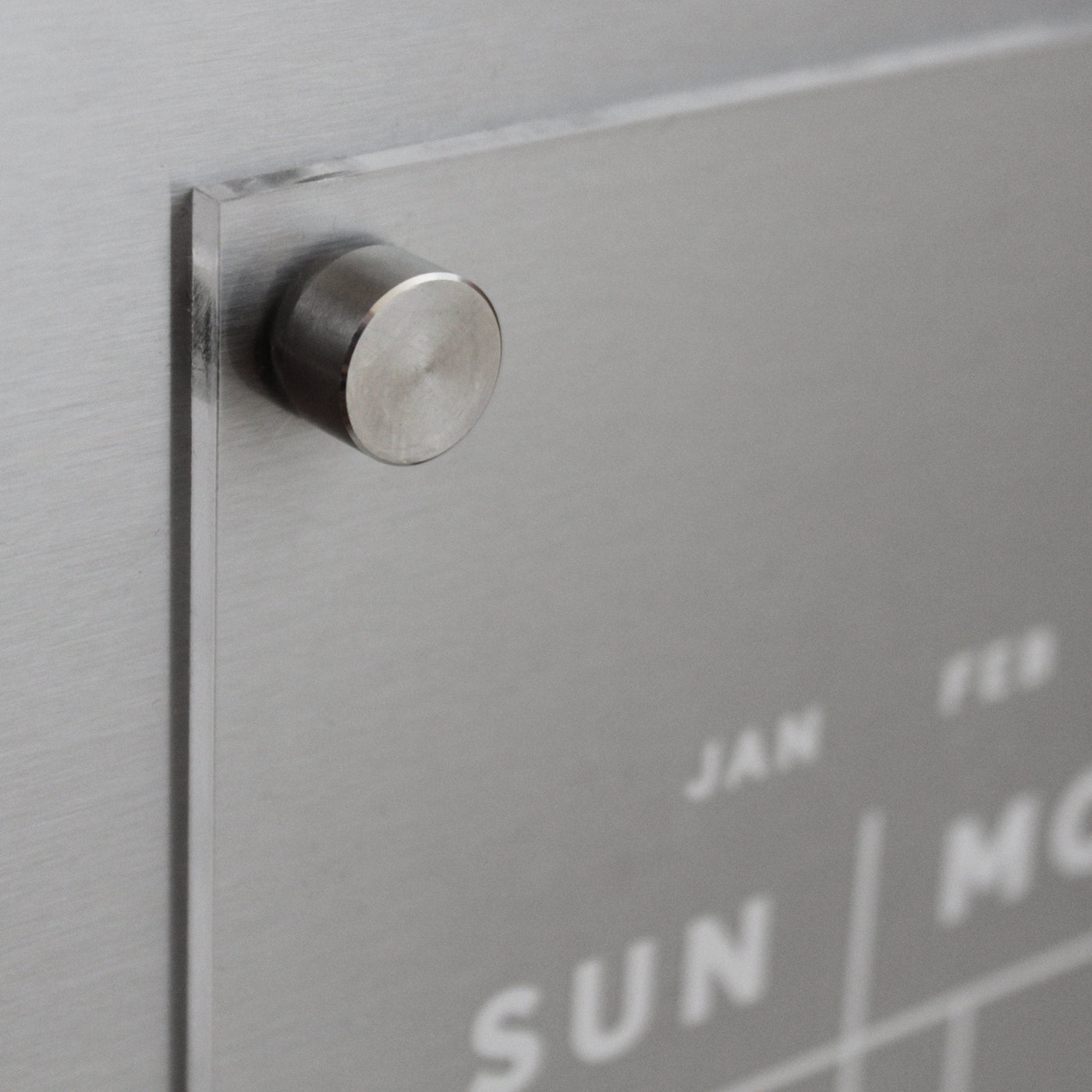 The Clear Acrylic Monthly Fridge Calendar by Girl Friday features a contemporary design, perfect for wet-erase markers. Mounted with round metal standoffs, days like SUN and MON appear in white on the sleek surface, adding a stylish touch to any space.