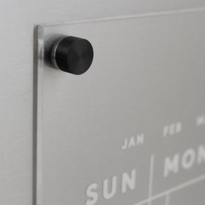 Acrylic Fridge Calendar | Custom Family Name by Girl Friday: Featuring a transparent acrylic surface with white days and months, this calendar is ideal for wet-erase markers. A sleek metal finish and round black magnet in the top left corner provide a modern touch.
