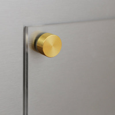 A close-up of a round, gold-colored metal knob on a Clear Acrylic Fridge To Do List by Girl Friday against a brushed metallic surface. The smooth, polished finish is reflective and ideal for use with wet-erase markers for customizable messages.