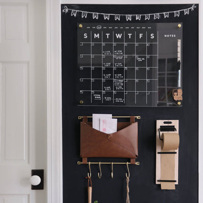The Girl Friday Shop features an Acrylic Calendar with side notes, white text, and a playful drawing. It includes a mail/key holder and roll of brown paper for extra notes, all easily updated with wet-erase markers.