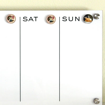 The Girl Friday whiteboard calendar emphasizes the weekend with a turkey icon on Saturday the 29th and a turkey leg on Sunday the 30th, separated by vertical lines. Ideal with Number Magnets - Thanksgiving! Turkey Day, it enhances your kitchens festive charm.